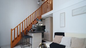 A modern apartment with a wooden staircase, a kitchen area, a dining table with chairs, and a sofa with cushions. - House with a garden and a nearby beach (Agde)
