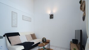 A modern living room with a sofa, a small side table, a television, and a decorative wall piece. - House with a garden and a nearby beach (Agde)