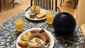 Un coin repas avec une table mise pour le petit-déjeuner, comprenant des croissants, des fruits et du jus.