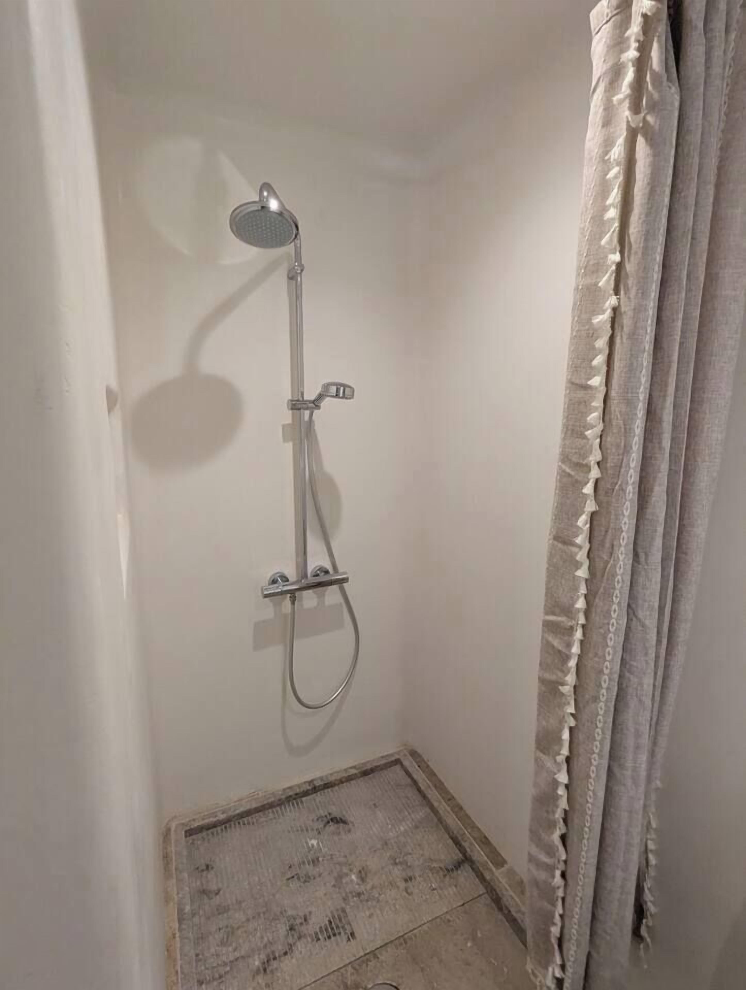 A small, enclosed shower area with a showerhead and handheld shower attachment.