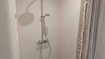A small, enclosed shower area with a showerhead and handheld shower attachment.