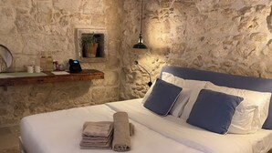 Un lit avec des draps blancs, deux oreillers bleus et une pile de serviettes beiges.