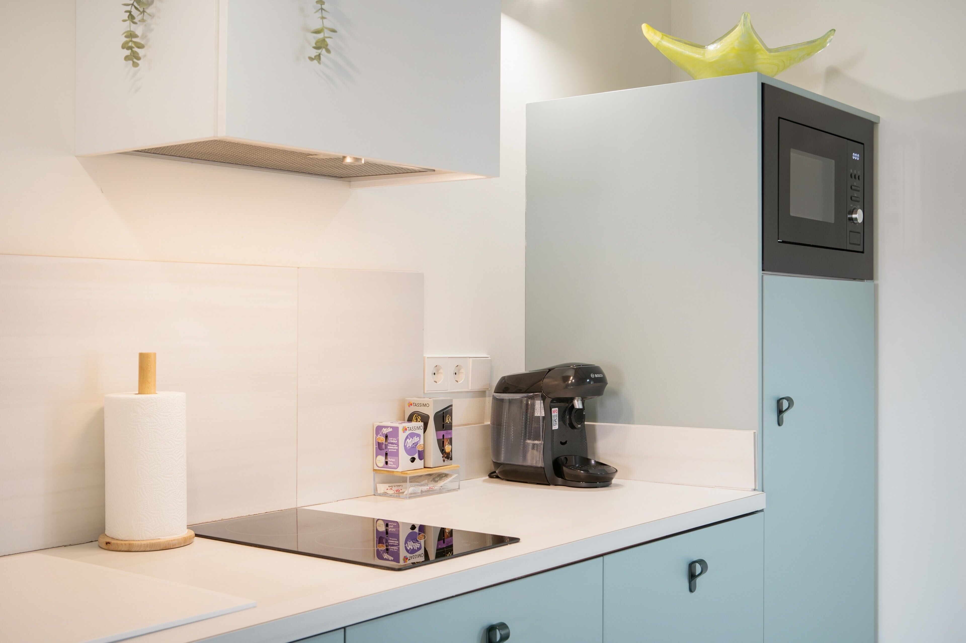 Una cocina con cafetera, dispensador de toallas de papel y microondas.