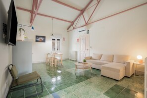 A living room with a sofa, a coffee table, a TV, a dining table with chairs, and a bench.