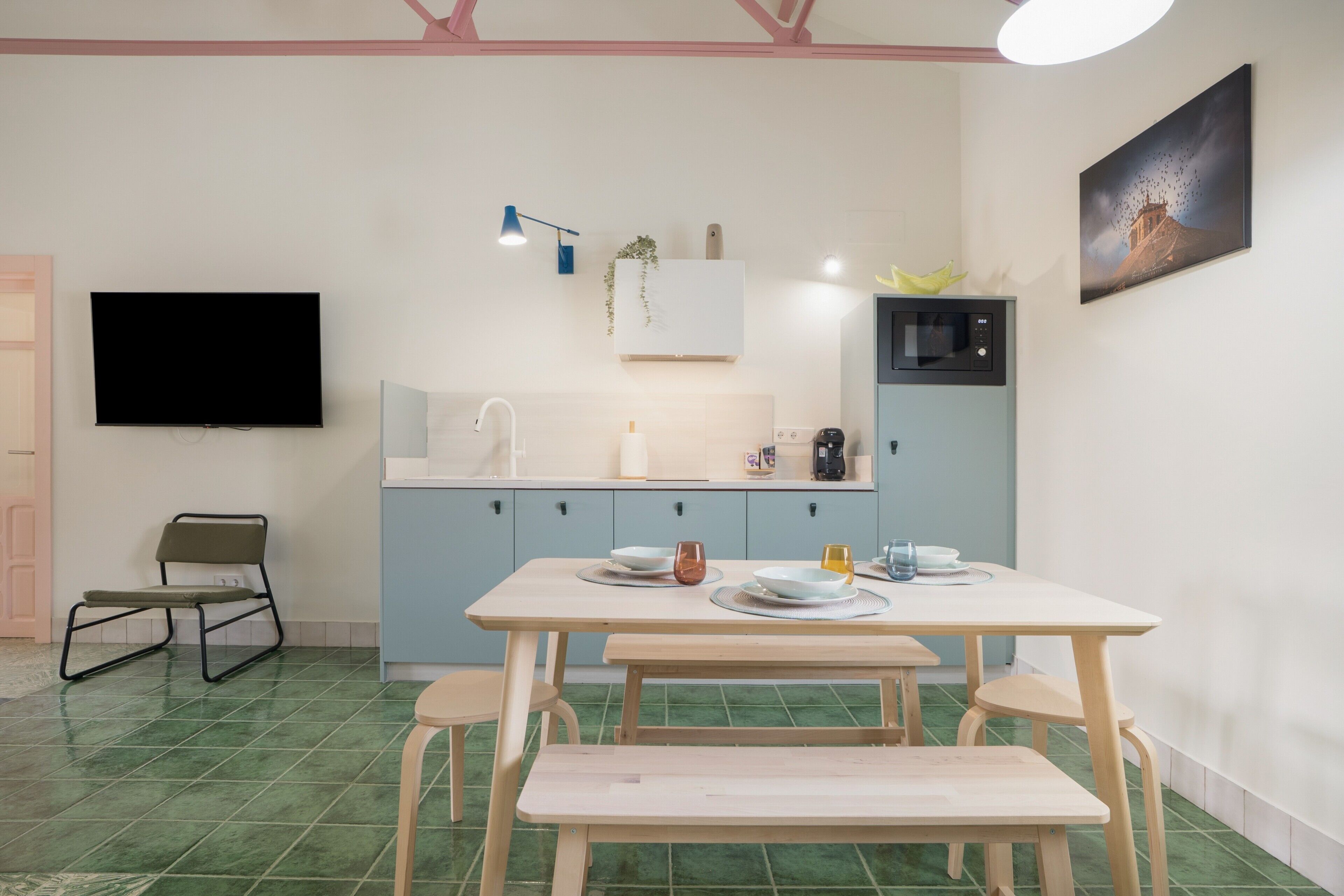 Una cocina moderna con una mesa de comedor, sillas, un televisor de pantalla plana y un microondas.