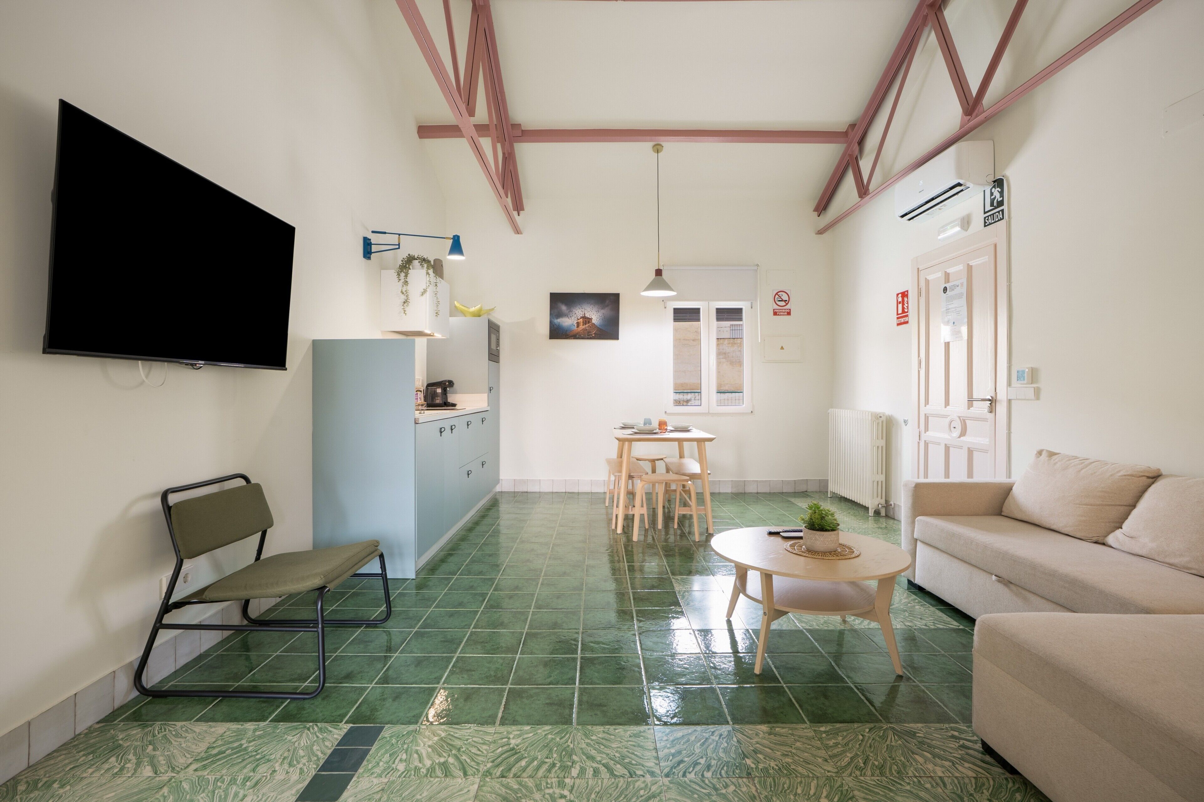 Un espacio habitable compacto con televisor de pantalla plana, kitchenette, comedor y sofá.