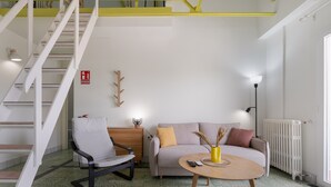 A modern living room with a staircase, a sofa, a chair, and a coffee table.
