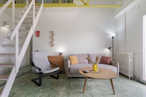 A modern living room with a staircase, a sofa, a chair, and a coffee table.