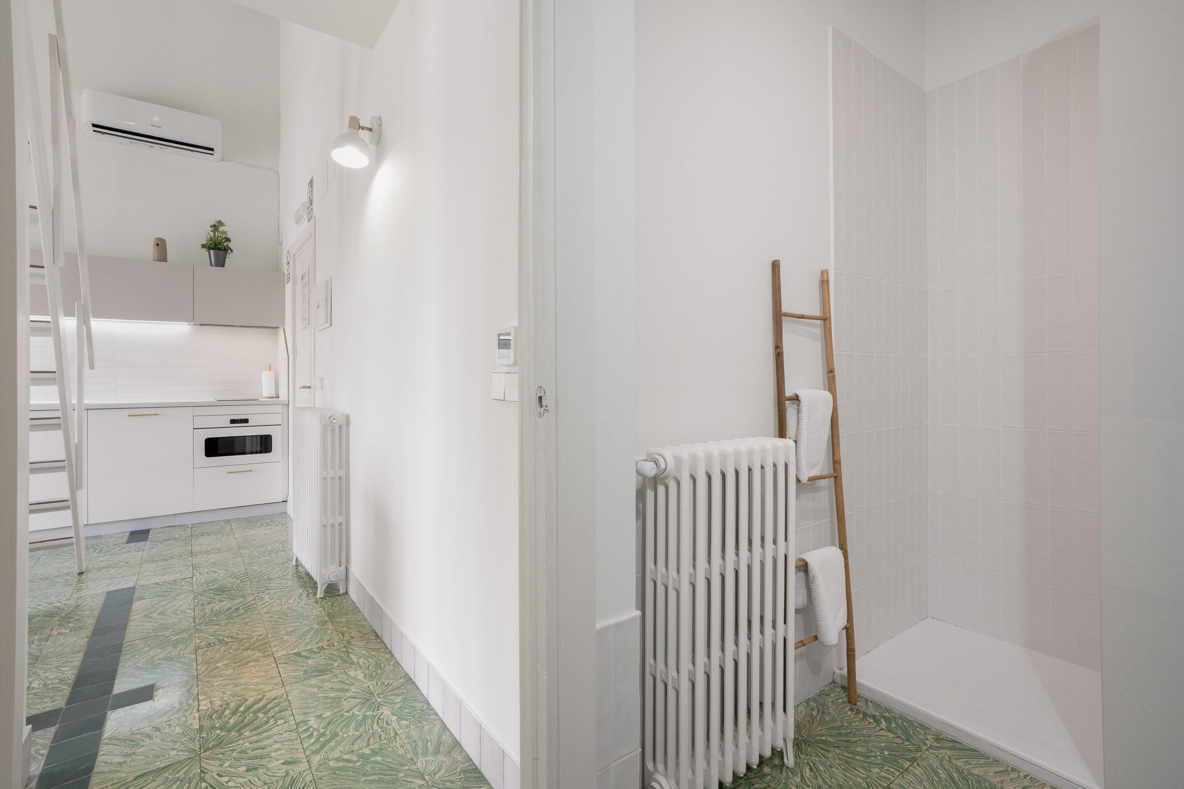 Un baño moderno con ducha, radiador y toallero.