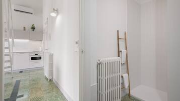 A modern bathroom with a shower, a radiator, and a towel rack.