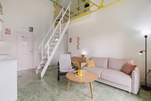 A modern living room with a staircase, a sofa, a coffee table, and a lamp.