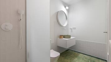 Une salle de bain équipée de toilettes, d’un lavabo, d’un miroir et d’une douche.