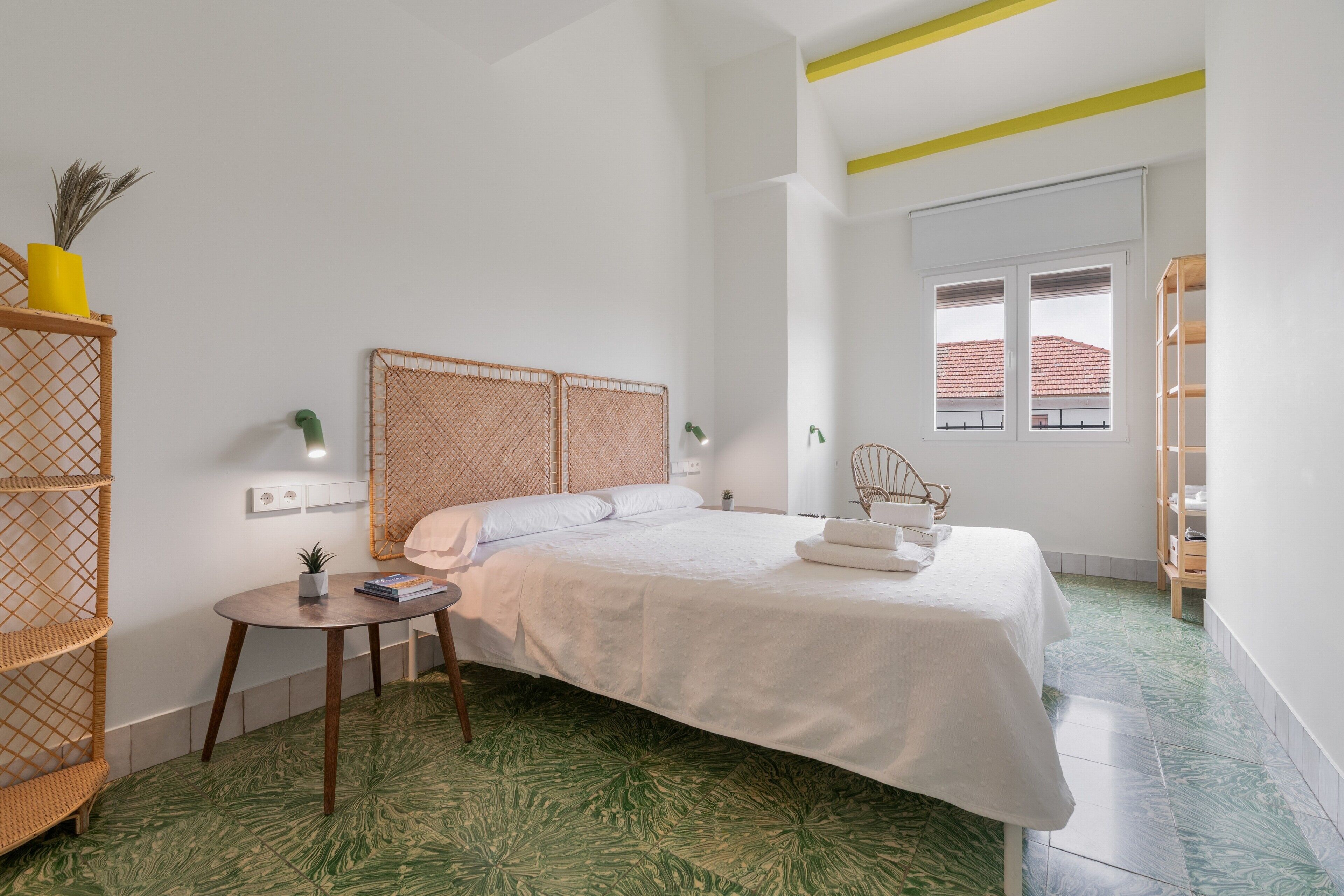 Un dormitorio con cama, mesita de noche y ventana.