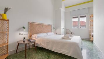 Un dormitorio con cama, mesita de noche y ventana.