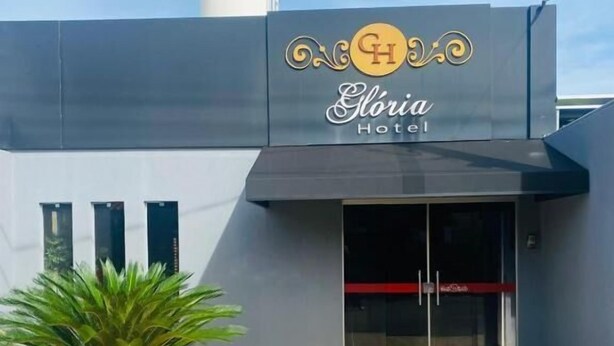 Entrada de hotel con diseño moderno, una palmera y cielo despejado.