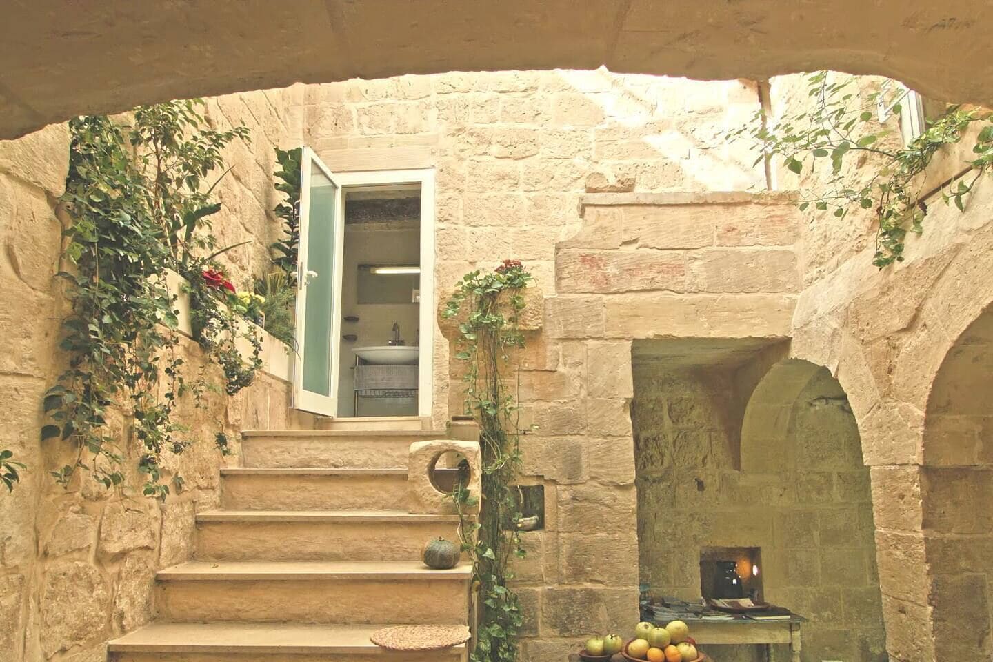 Eine Steintreppe führt zu einem Raum mit Fenster, Kamin und Obstschale.