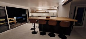 Eine moderne Küche mit einer Holz-Kochinsel, Barhocker und einem Essbereich mit Tisch und Stühlen.