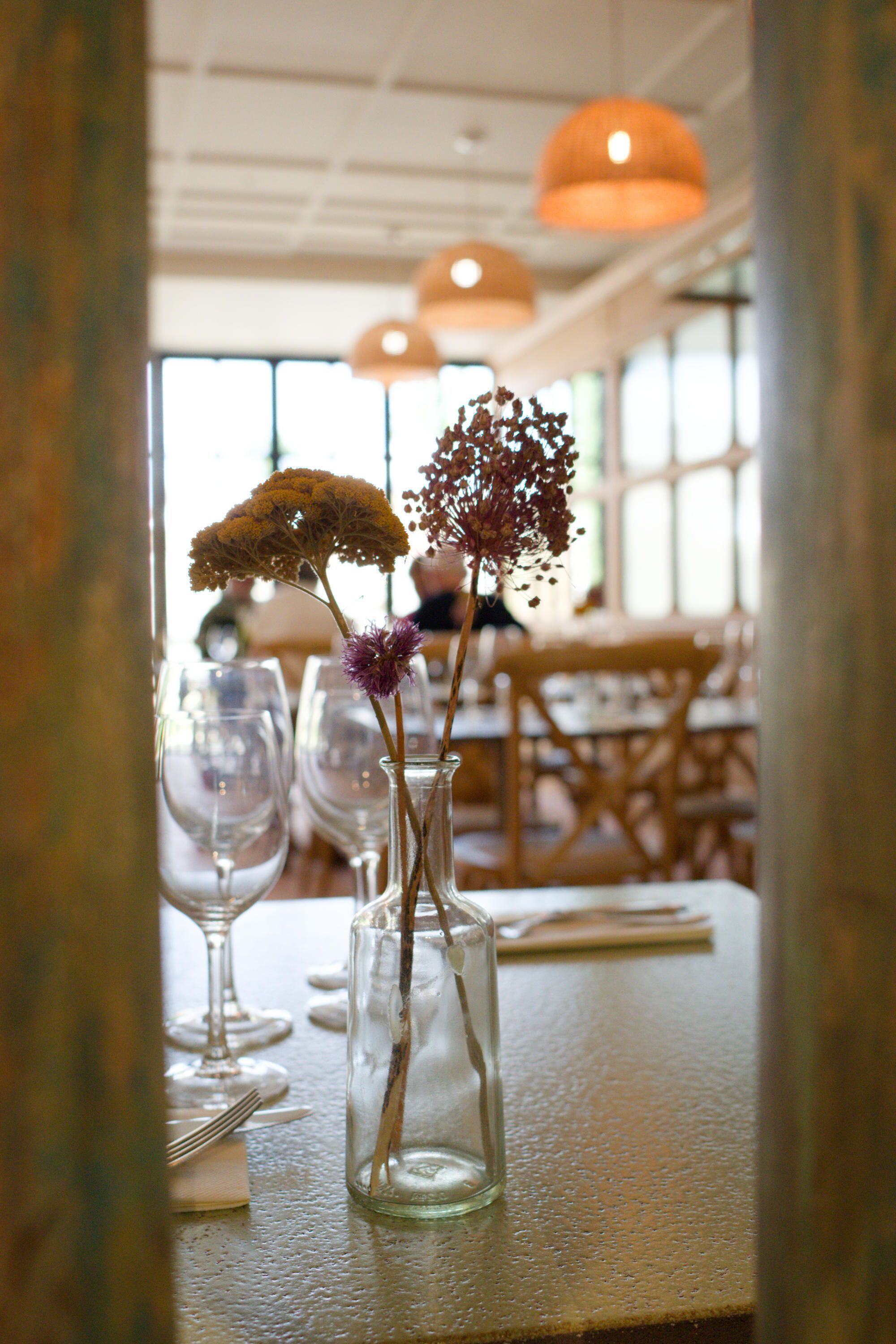 A dining table with a clear glass vase containing flowers, a fork, and a knife.