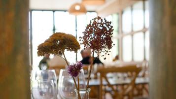 A dining table with a clear glass vase containing flowers, a fork, and a knife.