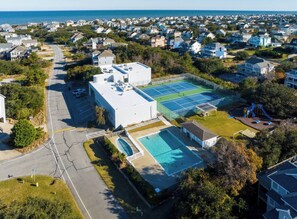 Ett bostadsområde med en stor byggnad, en tennisbana, en swimmingpool och en lekplats.