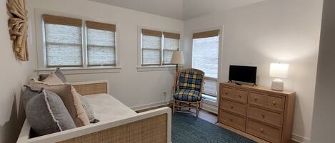 A bedroom with a bed, a chair, a dresser, and a television.