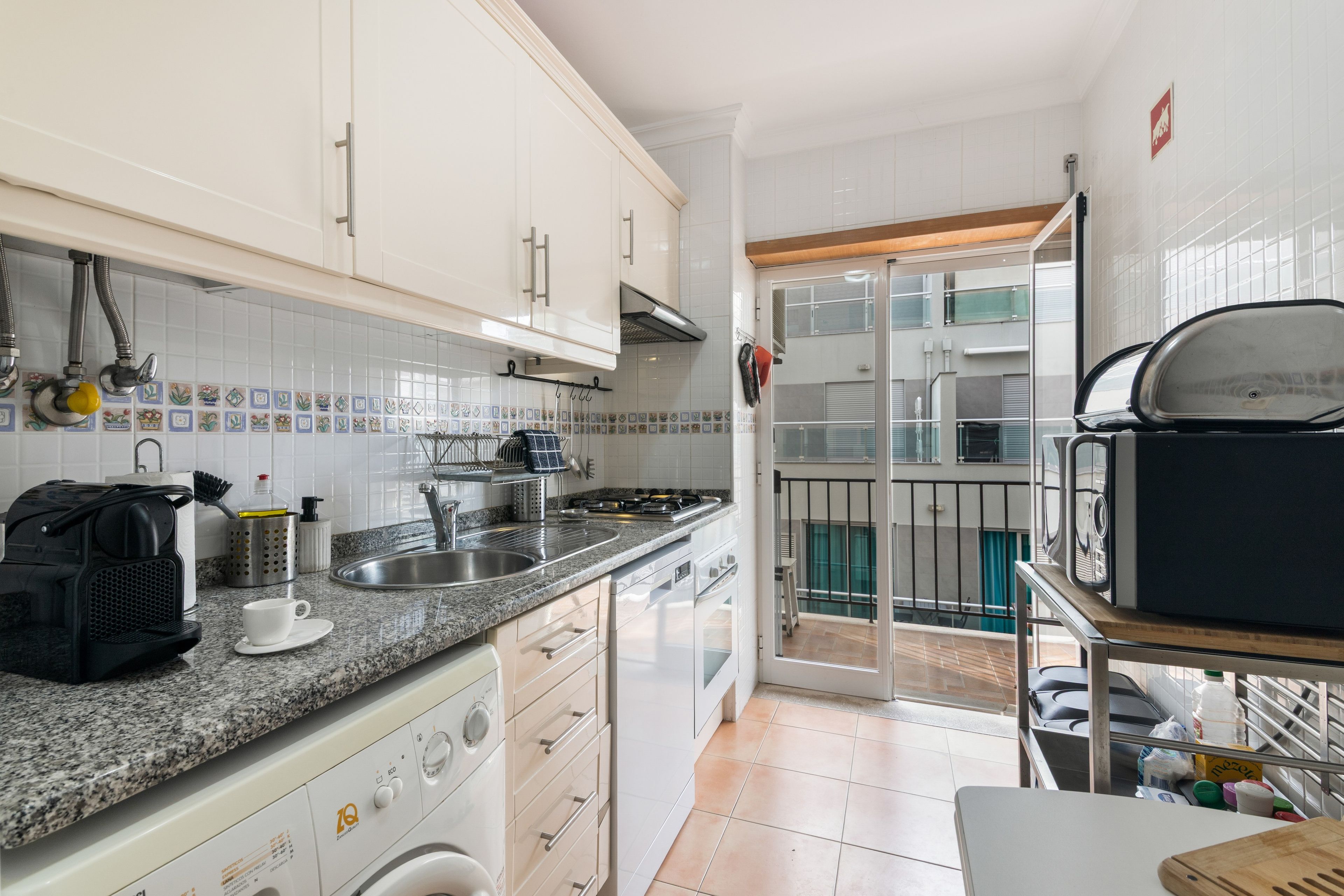 Een moderne keuken met witte kasten, een granieten aanrechtblad en een ingebouwde oven.