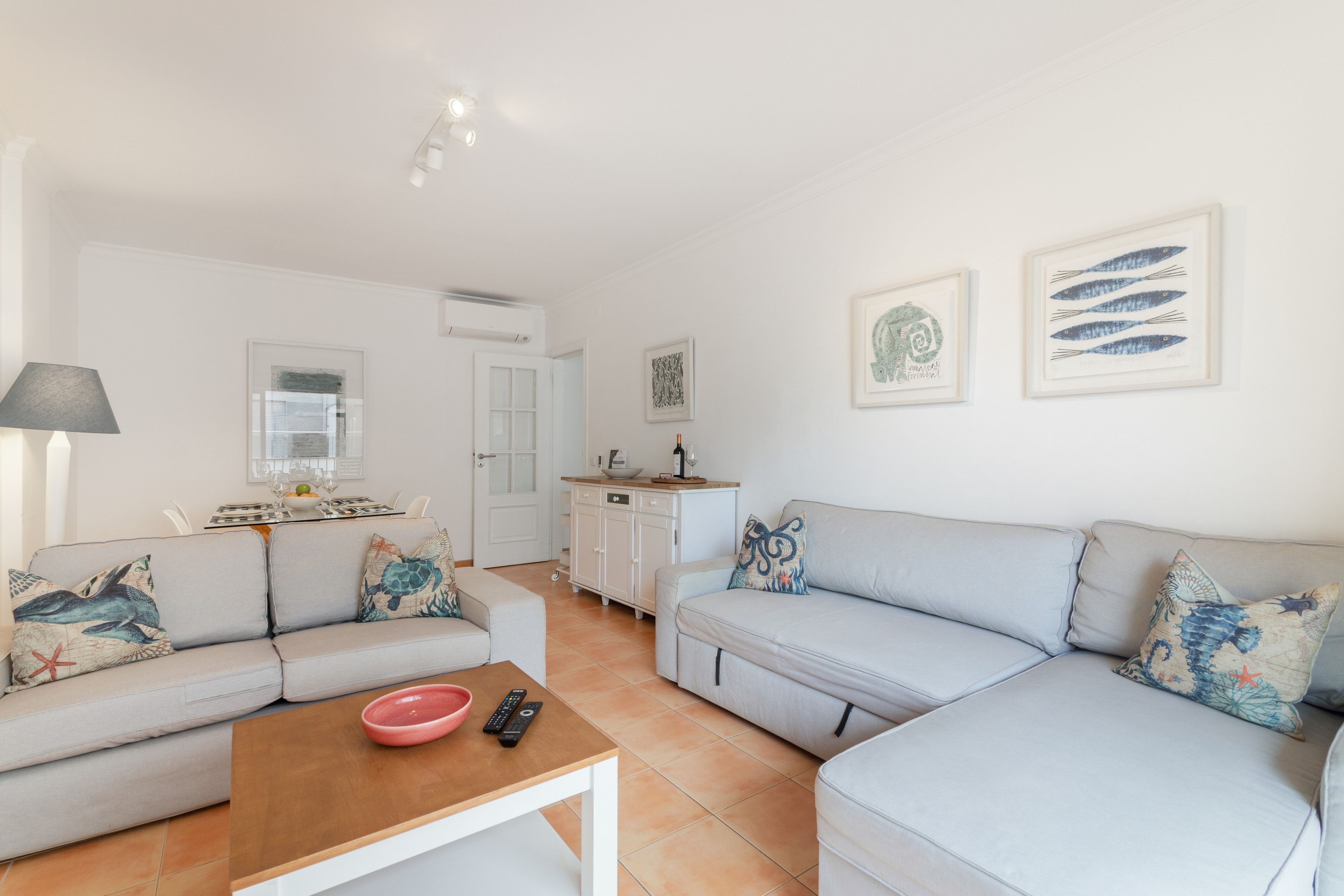 Una sala de estar moderna con un sofá, una mesa de centro y un comedor con una mesa dispuesta para dos.
