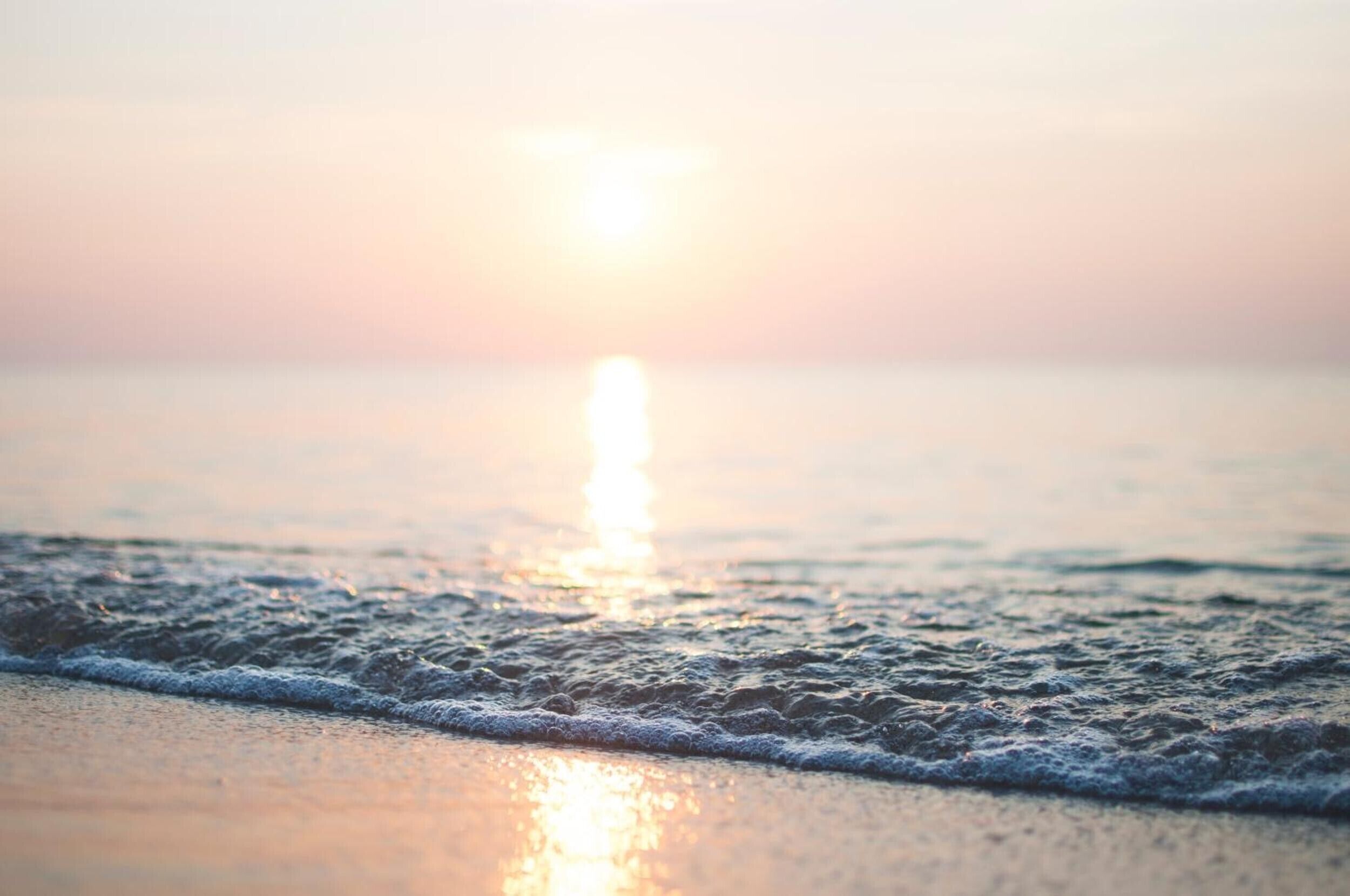 Een strand met golven en een zonsondergang.