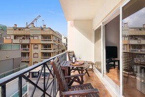 Ein Balkon mit Tisch, Stühlen und einem Fernseher.