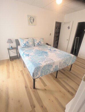 A bedroom with a bed, a nightstand, a lamp, and a door. - 1 bedroom pet friendly apartment on the first floor <br>- FREE parking<br>- ACs <br>- 7 minute walk from the beach.<br>- sleeps 3<br>- Queen bed and futon<br>- smart TV<br>- fast wifi<br>nroom before heading down to the beach! (Old Orchard Beach)