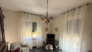 A living room with a marble floor, a wooden coffee table, a sofa, a television, and a chandelier.