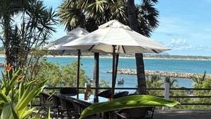 Terraza al aire libre con sombrillas, suelo empedrado y vista al mar.
