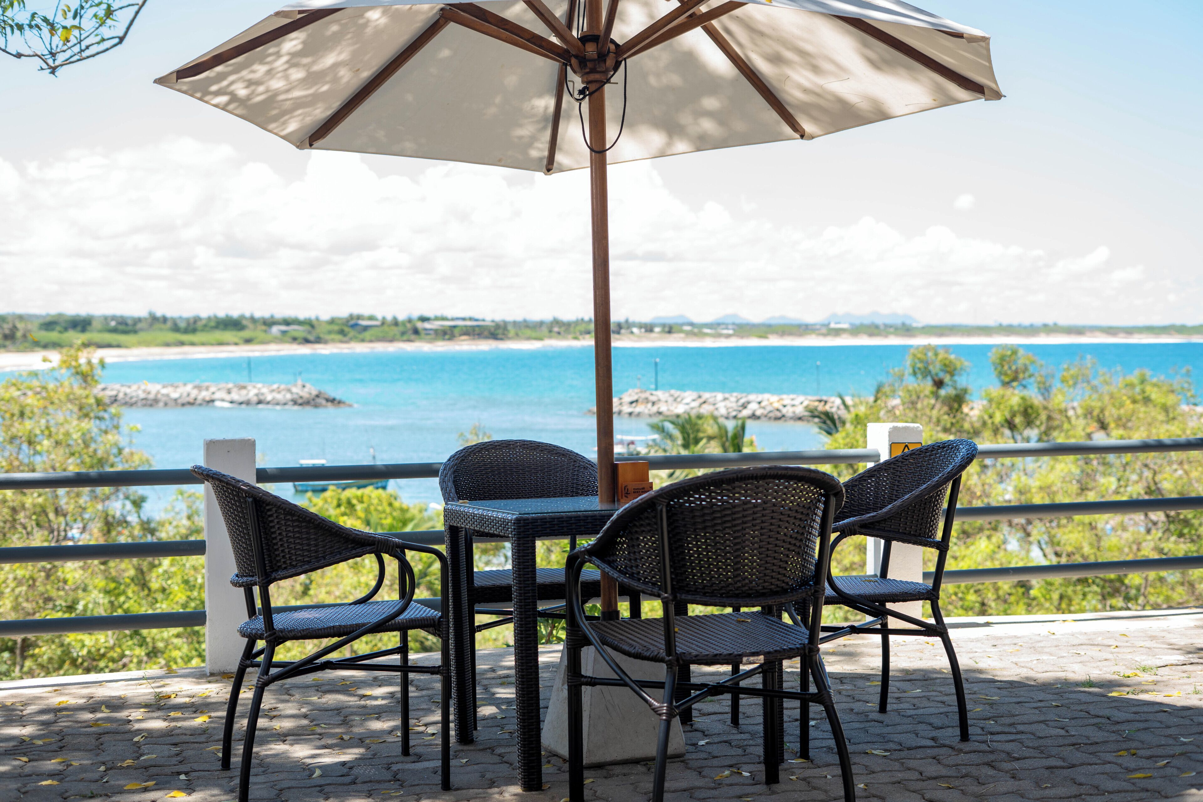 Um terraço com mesa e cadeiras, com vista para a praia e o mar.