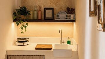 A compact kitchen with a stone backsplash, a white sink, and a small countertop.