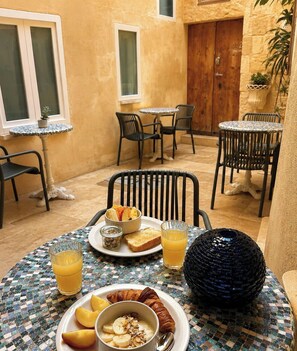 Et spiseområde med et bord dækket til morgenmad, inklusive croissanter, frugt og juice.