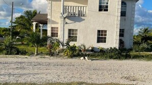 A two-story building with a balcony, a small porch, and a gravel driveway.