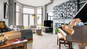 Ein Wohnzimmer mit einem Klavier, einer Couch, einem Fernseher und einem Kamin.