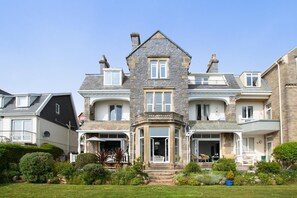 A large, multi-story house with a stone facade, multiple balconies, and a well-maintained garden. - 2 Bed in Langland (oc-hh142) (Newton)