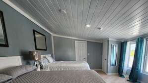 Ein Schlafzimmer mit zwei Betten, einer weißen Tür und einem Fenster mit Vorhängen.