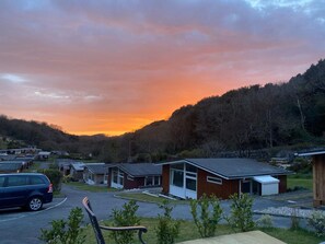 Ein Wohngebiet mit Häusern, einem geparkten Auto und einem Sonnenuntergang.