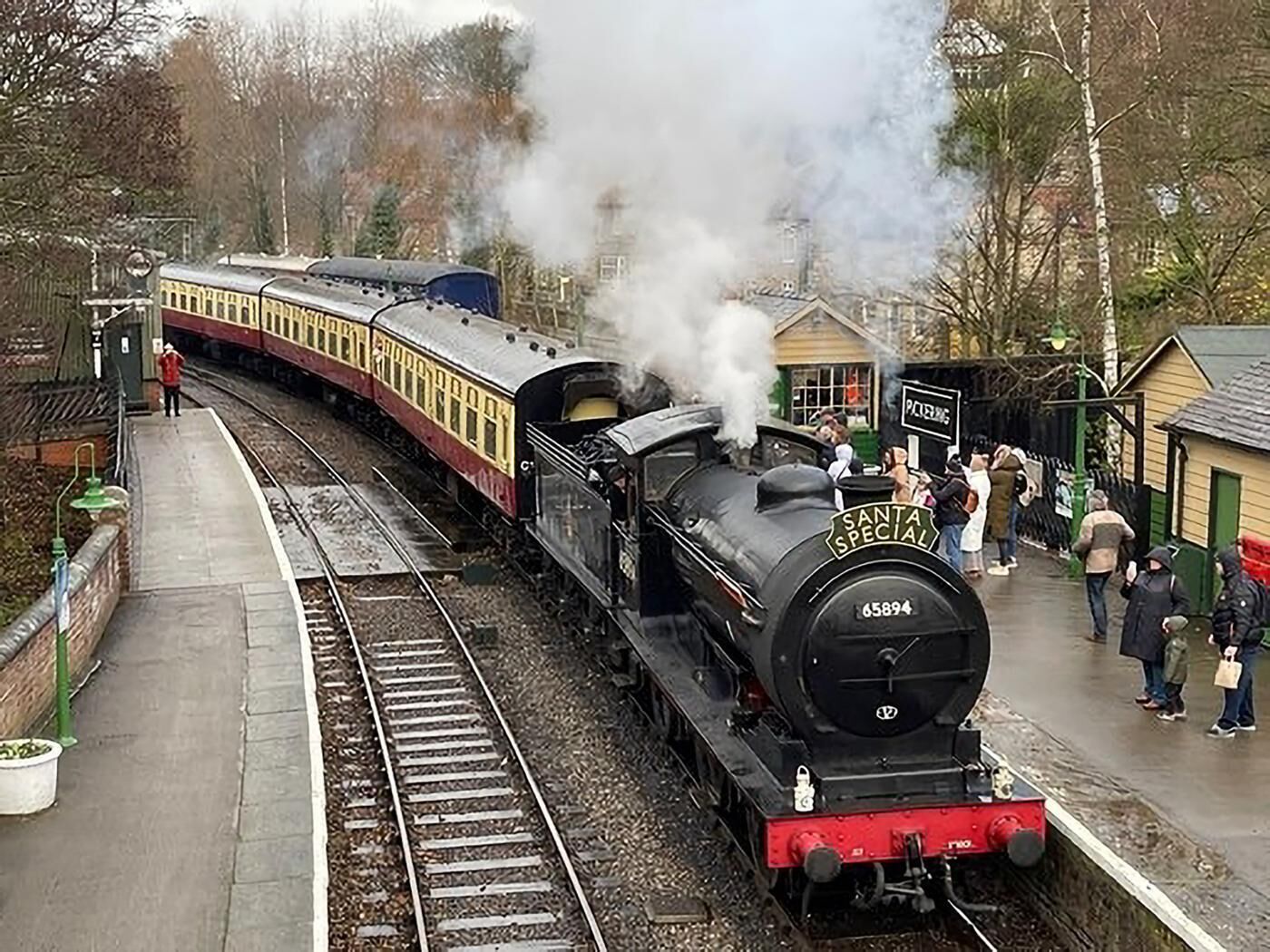 Une locomotive à vapeur portant le numéro 65894, sur le quai d’une gare.