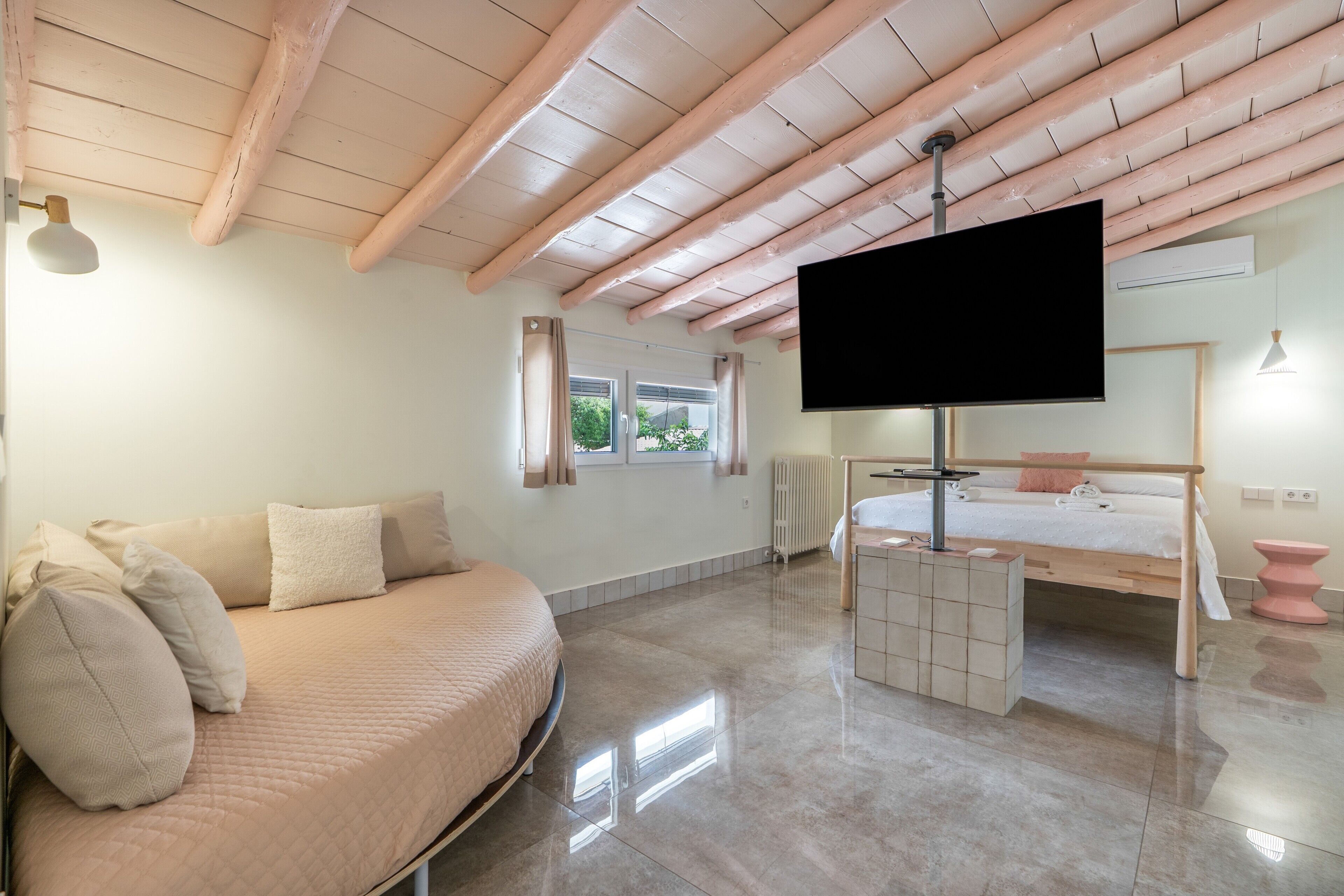 Ein modernes Schlafzimmer mit Bett, Sofa, Fernseher und Fenster.