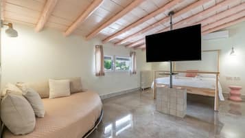 Un dormitorio moderno con cama, sofá, televisión y ventana.