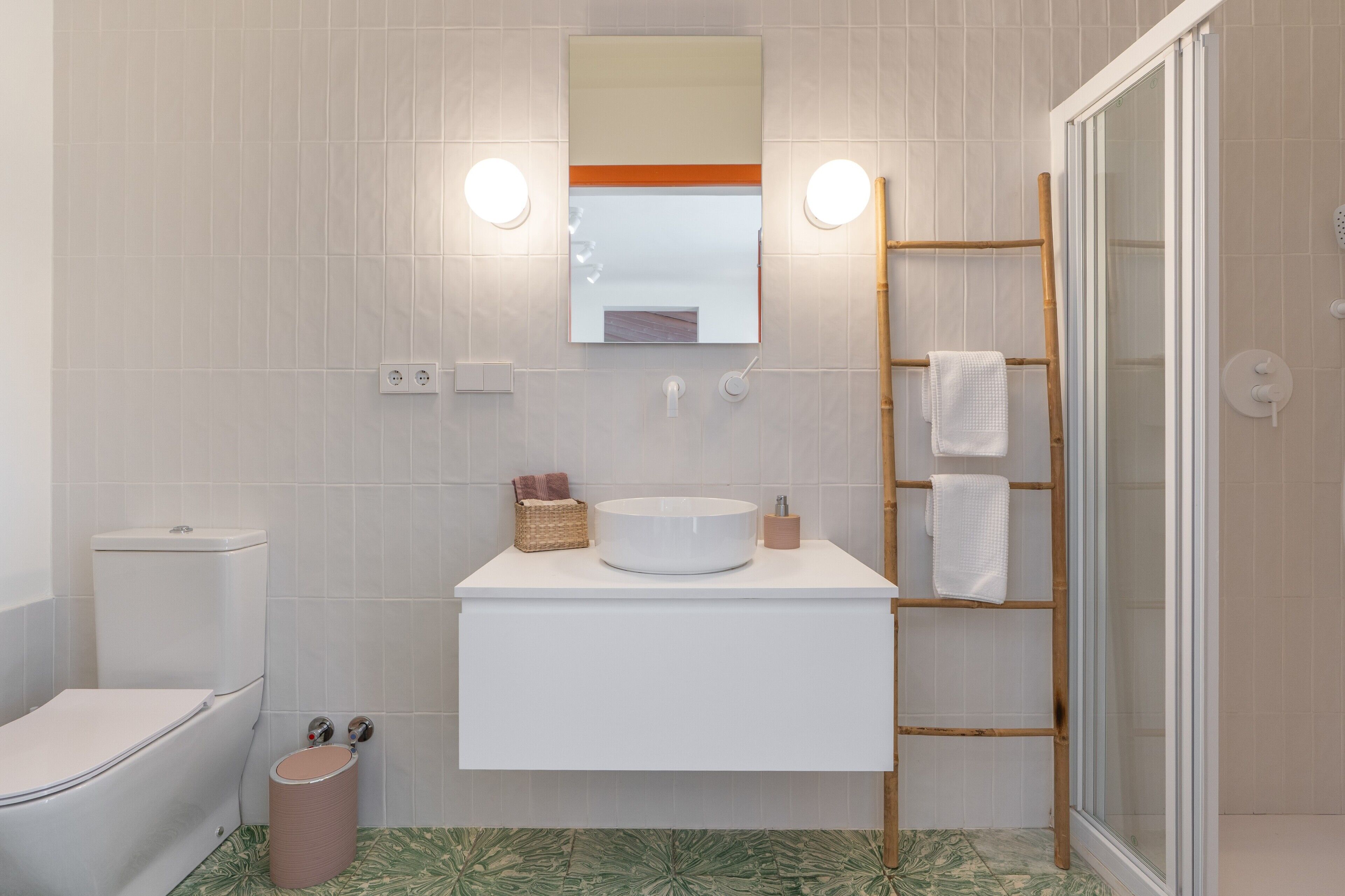 Une salle de bain équipée de toilettes, d’un lavabo, d’un miroir et d’une douche.