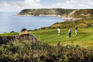 A golf course with a view of the sea and hills in the background. - 3 Bed in Mumbles (oc-hh620) (The Mumbles)