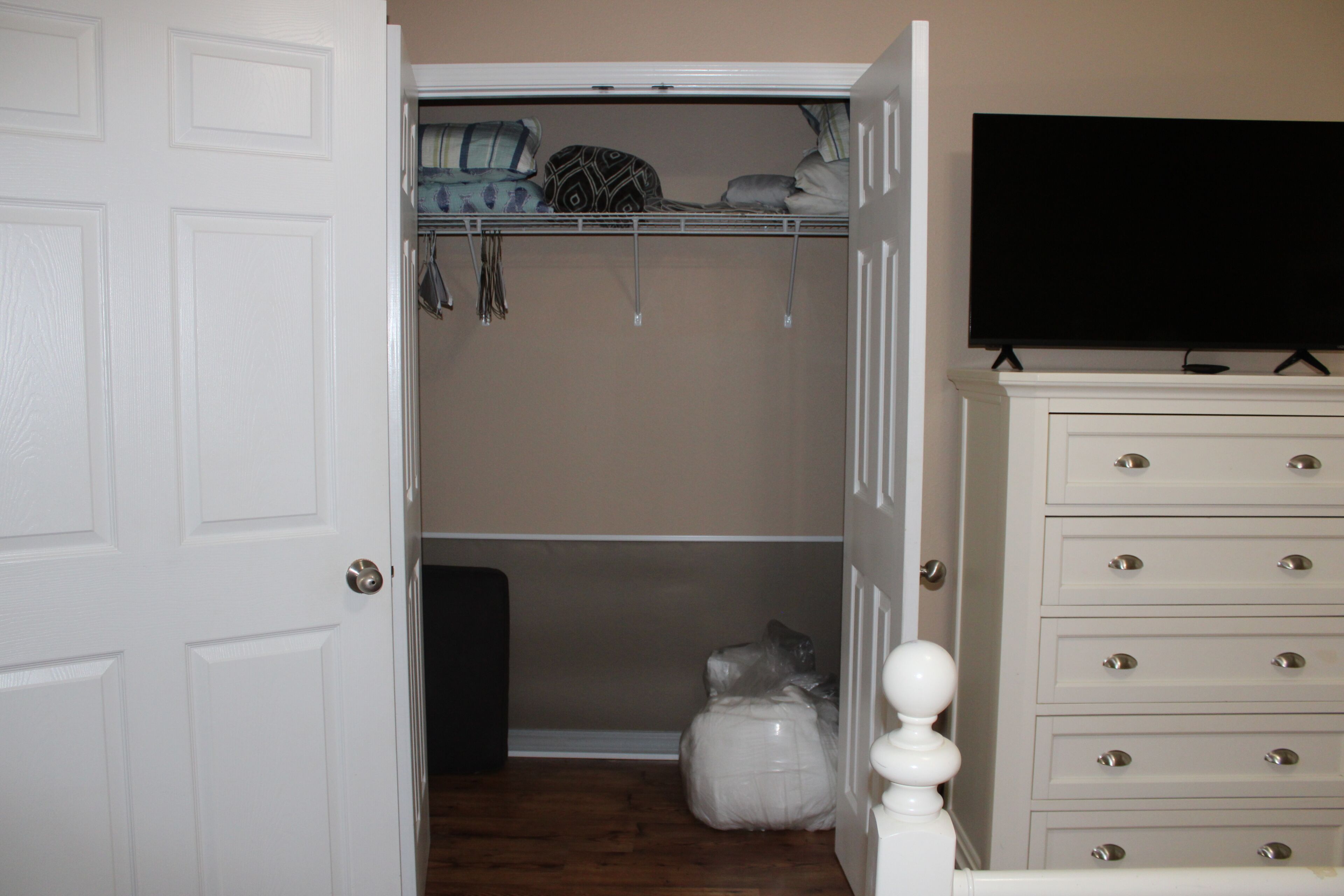 A closet with hanging space, a dresser, and a television on a stand.