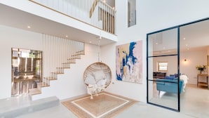 Ein modernes Interieur mit einer Treppe, einem Hängesessel und einem großen abstrakten Gemälde.