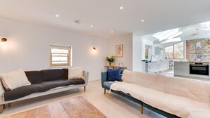 Ein modernes Wohnzimmer mit zwei Sofas, einem Couchtisch und einer Küche im Hintergrund.
