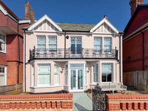 A two-story building with a balcony, a front door labeled 'FOREST LODGE,' and a bench outside. - 6 Bed in Southwold (oc-flgr) (Southwold)