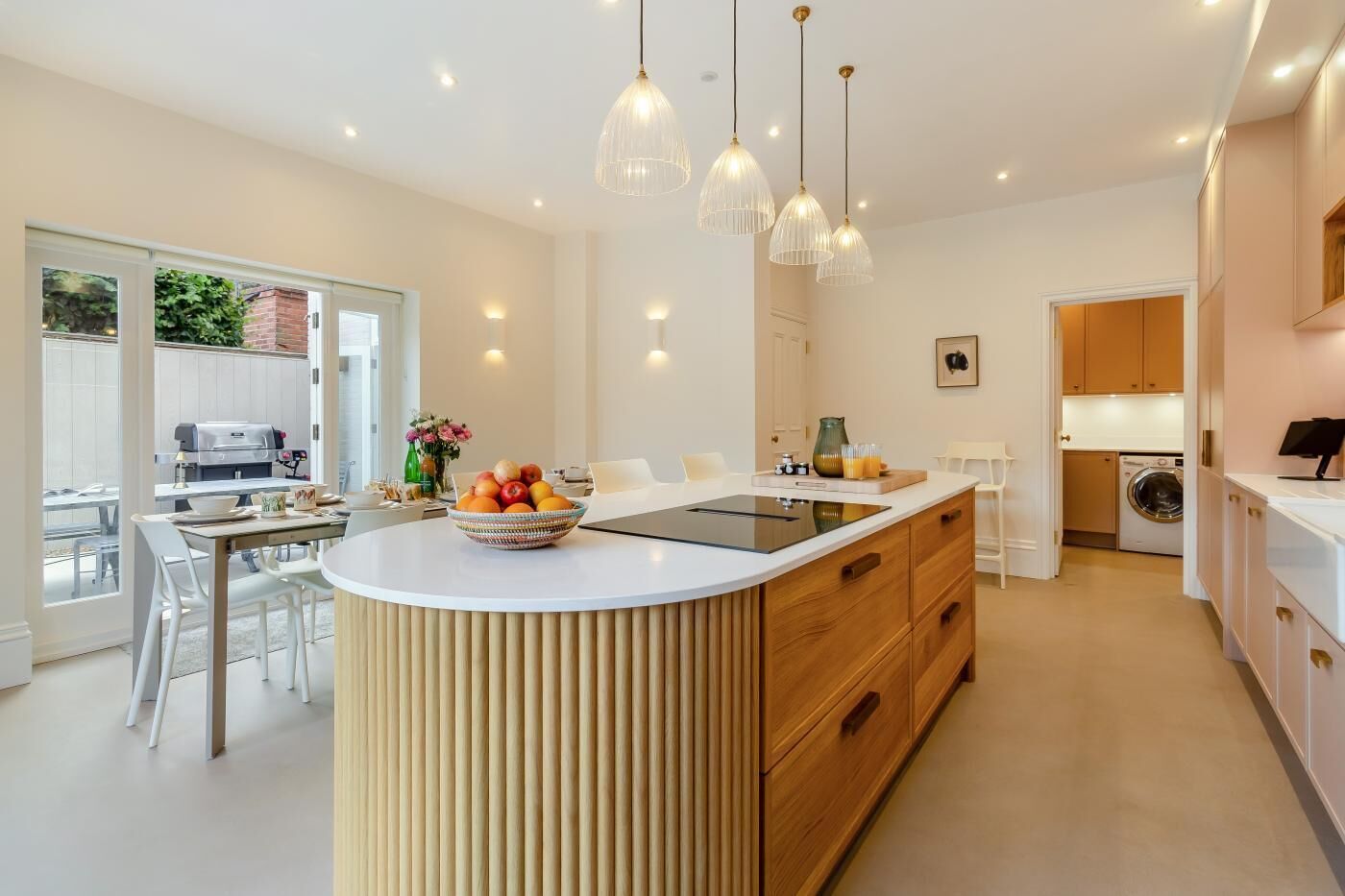 A modern kitchen with a central island, pendant lighting, and a view of the outdoor patio area.